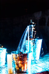 optical effect of water jets on illuminated metal cubes in the garden. traces in the water and selective blur.