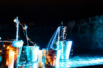 optical effect of water jets on illuminated metal cubes in the garden. traces in the water and selective blur.