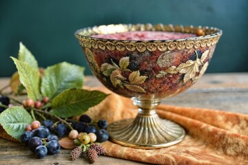 Decorative bowl filled with colorful fruit and surrounded by natural foliage, showcasing elegant design