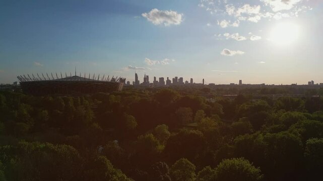 panorama of Warsaw city skyline and PGE Narodowy stadium at sunset, skyscrapers of downtown and green park, aerial top view 4k
