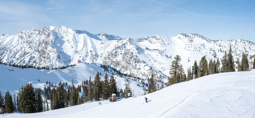 Panoramic photo of Deer Valley, single skier going down, snow covered caps, February 4, 2023