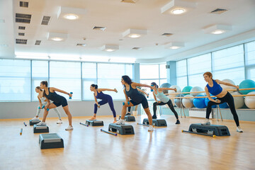 Fototapeta premium Group of women perform strength exercises with dumbbells