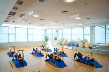 Obraz premium Ladies perform strength exercises with dumbbells, lying on special platforms