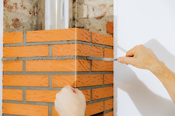 A young man makes brickwork on the chimney of a fireplace.