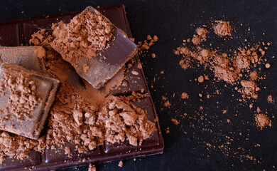 Black chococlate chips and cocoa powder on dark background.