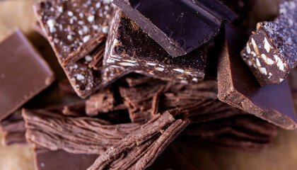 Different types of chocolate pieces on dark wood background.