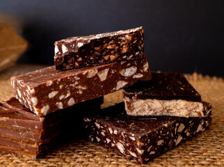 A stack of chocolates of different flavours on a rustic dark background.
