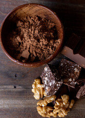 Vertical shot of cocoa powder, nuts and chococlates on wood.