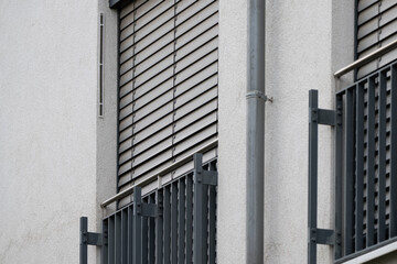 Fenster mit heruntergelassenem Rollladen und Balkongelaender