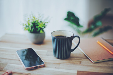 木製テーブルに置かれたコーヒーとスマホ