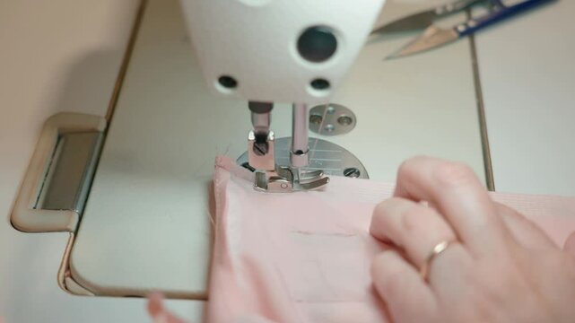 Close-up of the sewing machine, stitching stitching. Sewing production. Hands seamstress stitching clothes. Tailoring production. High quality 4k footage