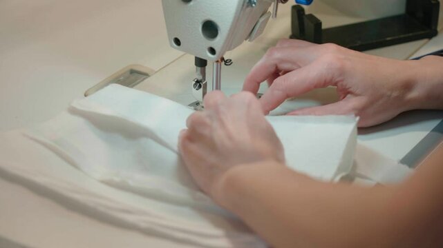 Close-up of the sewing machine, stitching stitching. Sewing production. Hands seamstress stitching clothes. Tailoring production. High quality 4k footage