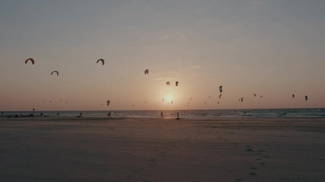 Seascape at sunset of kiteboarders kiting with kite and board in the sea with waves. High quality 4k footage