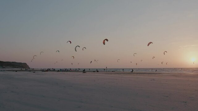 Seascape at sunset of kiteboarders kiting with kite and board in the sea with waves. High quality 4k footage