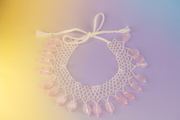 Light pink pendant ornate floral necklace made of beads on gradient background