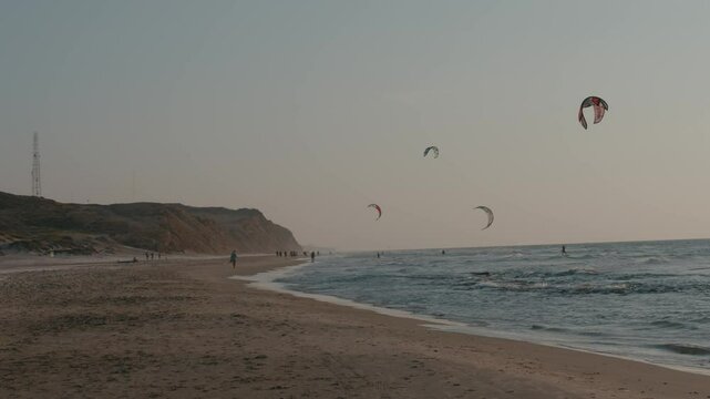 Seascape at sunset of kiteboarders kiting with kite and board in the sea with waves. High quality 4k footage