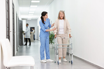 Nurse with senior woman in hospital hallway