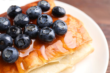 Tasty puff pastry with blueberries on wooden table, closeup