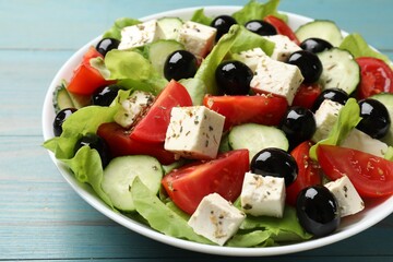 Delicious salad with feta cheese on light blue wooden table, closeup