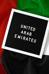 Text UNITED ARAB EMIRATES on background waving flag of UAE. National holiday, Independence Commemoration Day Muslim, congratulations. Arabian holidays. Advertisement of Dubai celebration 