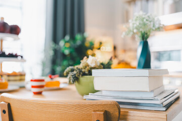 Books are piled up on the dining table with the kitchen in the background.