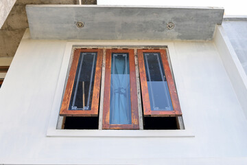 A modern window with a wooden frame and glass panes, partially open to allow natural light and ventilation
