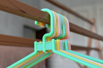 A bunch of colorful plastic hangers hanging on a wooden clothesline
