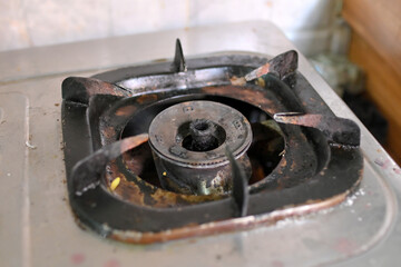 A close-up of a heavily soiled gas stove burner
