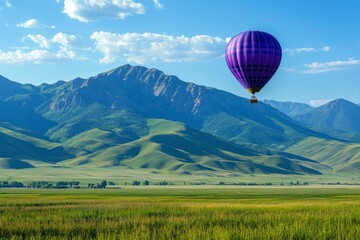 Naklejka premium A Purple Hot Air Balloon Ascending Above Green Rolling Hills and Mountains