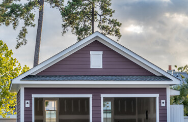 Deep purple gable roof with white frame air vent above an under construction two car garage