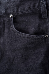 Close-up of blue denim jean pocket on black leather jacket, detailed texture and stitching