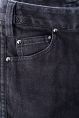Close-up of blue denim jean pocket on black leather jacket, detailed texture and stitching