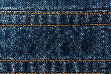 An image of close-up blue denim jeans fabric showing detailed texture with a dark blue color and a...