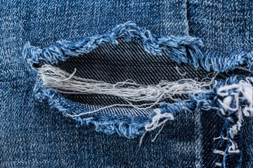 Close-up of blue ,tear ,ripped denim jeans with visible seam and zipper, emphasizing the textured...