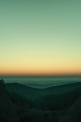 Obraz premium Colorful sky fading into forest covered hills at sunset