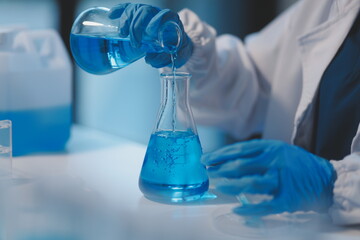 Group of dedicated scientist conduct chemical experiment in medical laboratory, carefully drop precise amount of liquid from pipette into test tube for vaccine drug or antibiotic development. Neoteric
