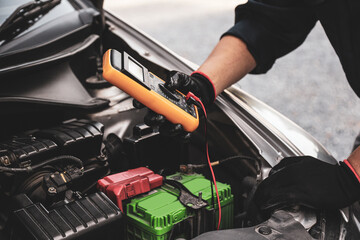Car mechanic use voltmeter to check voltage battery low energy problem for car care service maintenance and re charger or jump start or change battery replacement.