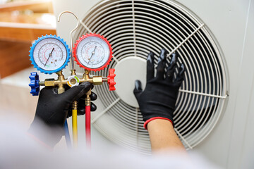 Technician using manifold gauge measuring tool checking refrigerant pump filling home air...
