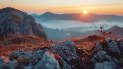 Obraz premium Serene mountain landscape at sunrise, with soft warm light bathing foreground rocks and grass