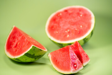 The watermelon and the sliced watermelon piece in green background