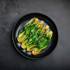 Grilled Pak Choi or Bok Choy on a black background, top view