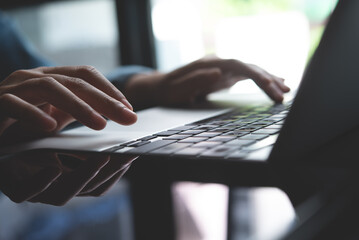 Closeup of business woman hand typing and working on laptop computer, searching the information, surfing the internet with digital tablet on office table, remote work, online job concept