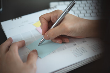 Close-up of agenda organize, business woman writing on sticky note with calendar planner, agendar...