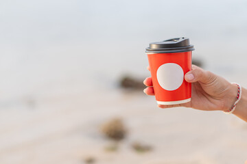 Hand Holding a Red Coffee Cup Outdoors