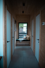 A modern hallway with multiple doors and a cozy seating area bathed in natural light during the late afternoon