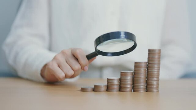 coins money stack growing with magnifier glass. Money saving, Inflation, tax, cash flow, Job search, hiring and research development concepts