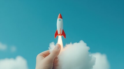 A hand holds a small rocket as it ignites, sending flames and smoke upward against a bright blue sky