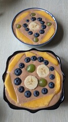 A bowl of bananas, blueberries, mangoes, and grapes on a table