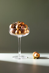 Christmas background , glass filled with elegant gold and copper xmas ornaments at green backdrop with shadow .The festive image for winter holiday season.