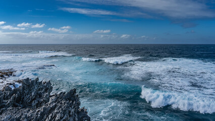 The endless blue ocean. The waves are raging, beating against the rocks. White foam on the surface...